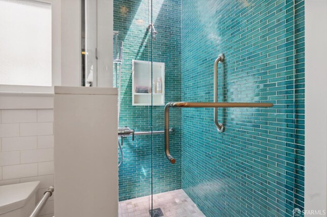 bathroom with tile walls, toilet, and a shower stall