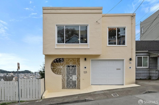 view of front of house featuring fence, an attached garage, and stucco siding