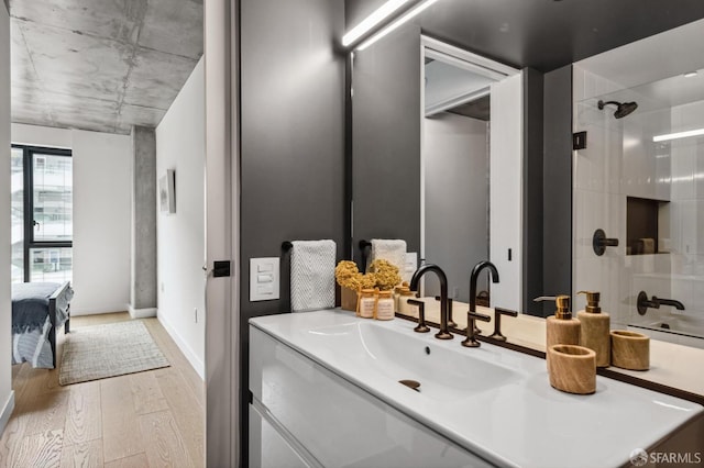 bathroom with hardwood / wood-style flooring, vanity, and a shower