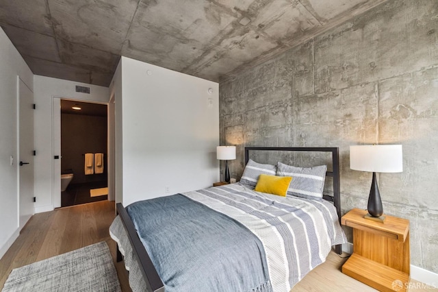 bedroom with connected bathroom and hardwood / wood-style floors