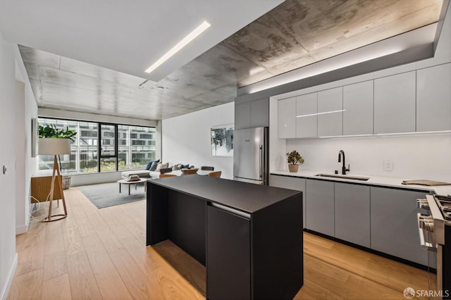 kitchen featuring a kitchen island, sink, light wood-type flooring, and stainless steel appliances