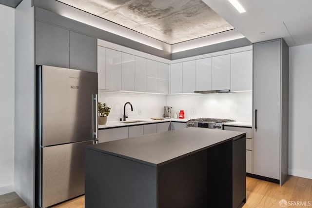 kitchen with sink, stainless steel fridge, stove, light hardwood / wood-style floors, and a kitchen island