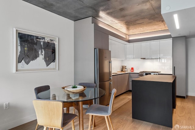 kitchen with white cabinetry, stainless steel fridge, light wood-type flooring, a kitchen island, and range