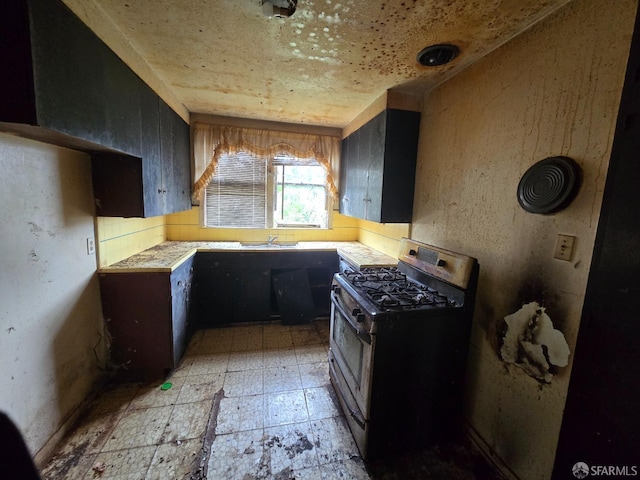 kitchen featuring light countertops, light floors, and stainless steel gas range oven