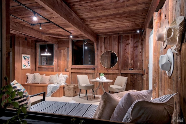 living area with beam ceiling, wood walls, rail lighting, and wooden ceiling