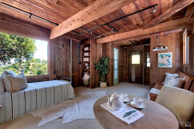 bedroom with wooden walls, beamed ceiling, rail lighting, and wood ceiling