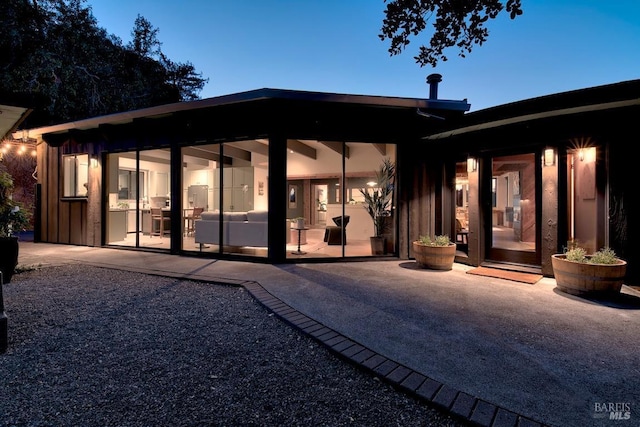 back house at dusk with a patio area and an outdoor living space