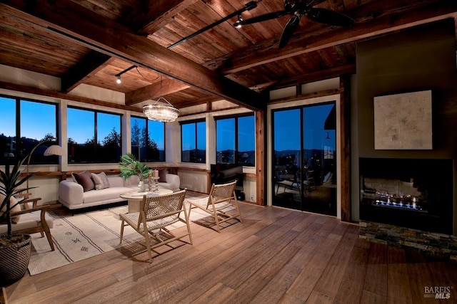 sunroom featuring ceiling fan with notable chandelier, beam ceiling, wooden ceiling, and rail lighting