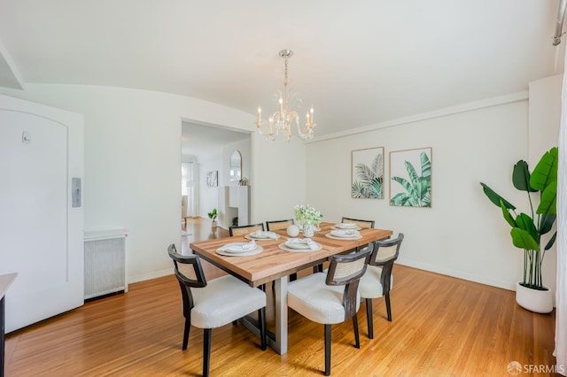 dining room with light hardwood / wood-style floors, a notable chandelier, and radiator heating unit