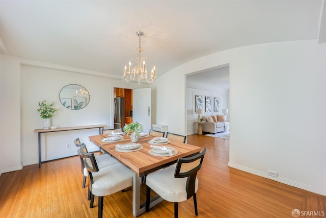 dining area with light hardwood / wood-style flooring and a notable chandelier