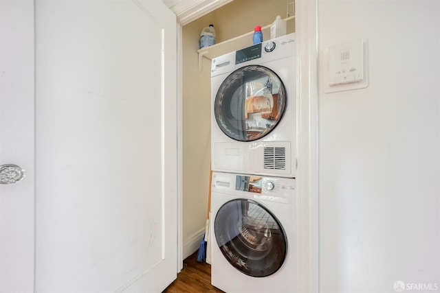 laundry room with stacked washer / drying machine and dark hardwood / wood-style flooring