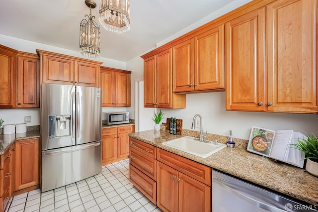 kitchen featuring an inviting chandelier, light stone countertops, sink, pendant lighting, and stainless steel appliances