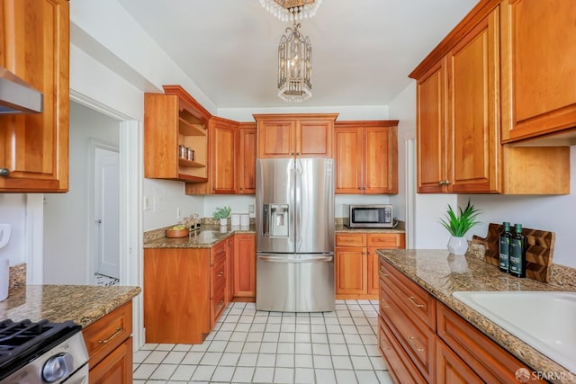 kitchen featuring decorative light fixtures, light stone counters, stainless steel appliances, and an inviting chandelier