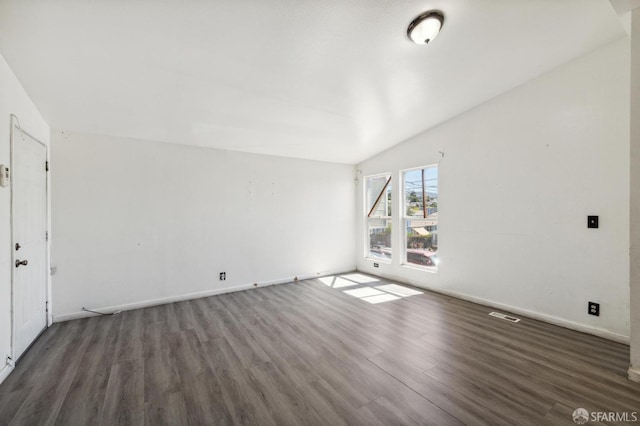 empty room featuring dark wood-type flooring and vaulted ceiling