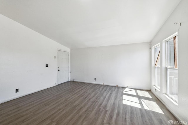 empty room with vaulted ceiling and hardwood / wood-style flooring