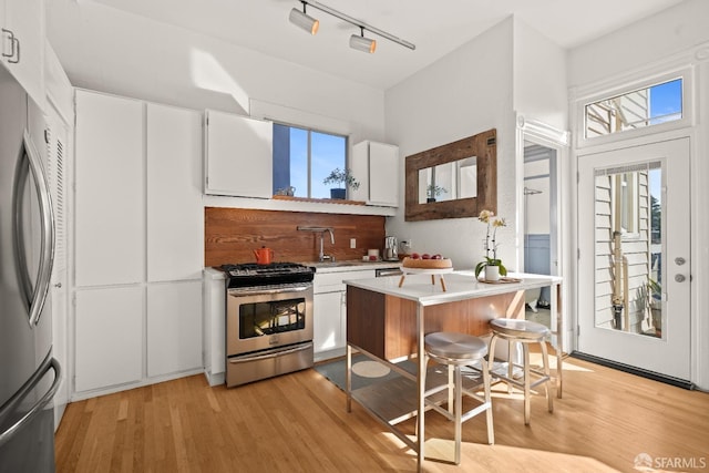 kitchen featuring stainless steel appliances, light wood-type flooring, light countertops, and white cabinetry