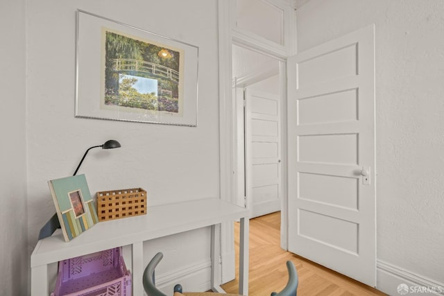 corridor featuring a textured wall and light wood-style flooring