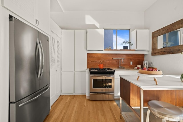 kitchen featuring appliances with stainless steel finishes, light countertops, light wood-style floors, white cabinetry, and a sink