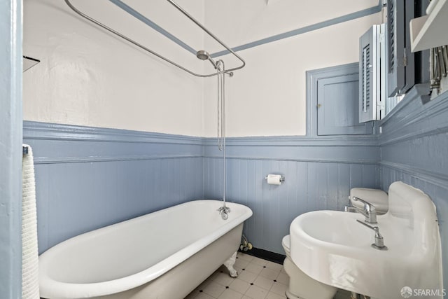 full bath featuring a sink, a wainscoted wall, and a freestanding tub