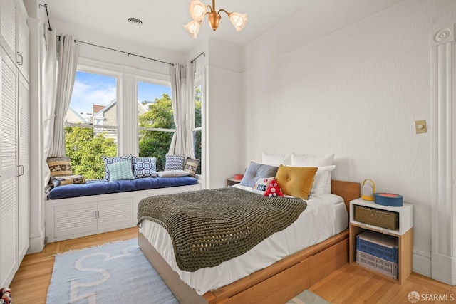 bedroom featuring an inviting chandelier, visible vents, and wood finished floors