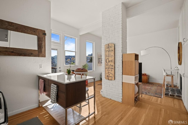 kitchen featuring a kitchen bar, light countertops, light wood-style floors, a peninsula, and baseboards