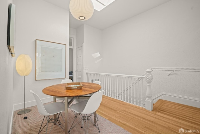 dining area with a skylight, wood finished floors, and baseboards