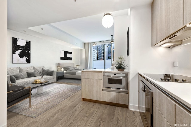 201 Folsom St Unit 2A, San Francisco, CA 94105 - kitchen featuring black electric stovetop, oven, light wood finished floors, and light brown cabinetry