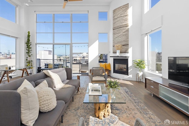 living room featuring a multi sided fireplace, hardwood / wood-style floors, and a high ceiling