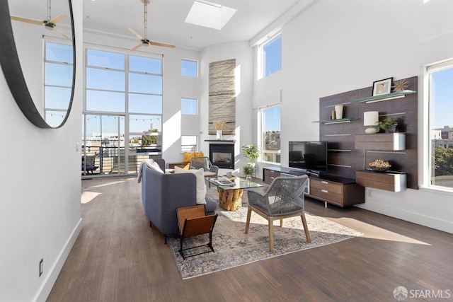 living room featuring dark hardwood / wood-style flooring, a towering ceiling, and a skylight