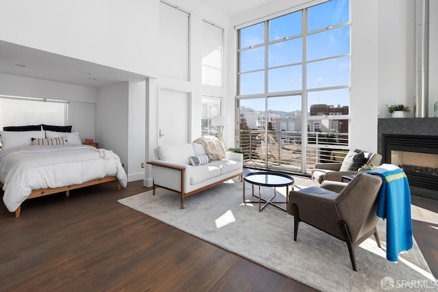 bedroom with dark hardwood / wood-style floors, a high ceiling, and a multi sided fireplace