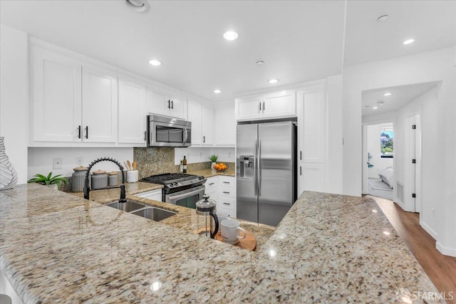 114 Emerald Cove Ter, San Francisco, CA 94134 - kitchen featuring appliances with stainless steel finishes, a sink, light stone countertops, wood finished floors, and white cabinetry