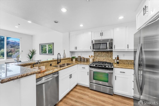 114 Emerald Cove Ter, San Francisco, CA 94134 - kitchen with stainless steel appliances, a sink, a peninsula, white cabinets, and stone counters