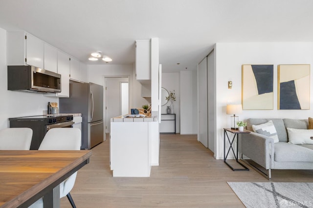 389 Belmont St Unit 306, Oakland, CA 94610 - kitchen with stainless steel appliances, white cabinets, light wood-type flooring, tile countertops, and open floor plan