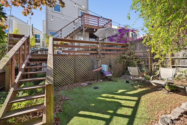 view of yard with a deck, fence, and stairs