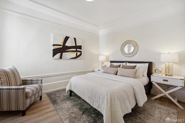bedroom featuring crown molding, baseboards, and wood finished floors
