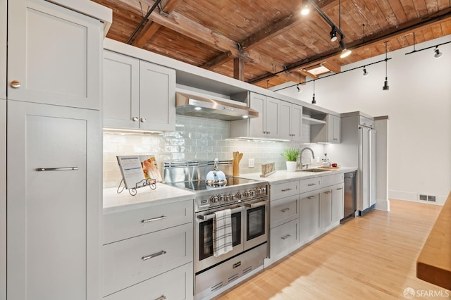 355 Bryant St Unit 411, San Francisco, CA 94107 - kitchen featuring appliances with stainless steel finishes, wall chimney exhaust hood, a wood ceiling with exposed beams, open shelves, and track lighting