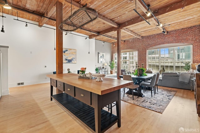 355 Bryant St Unit 411, San Francisco, CA 94107 - dining room featuring a wooden ceiling with exposed beams, rail lighting, brick wall, light wood-type flooring, and a high ceiling