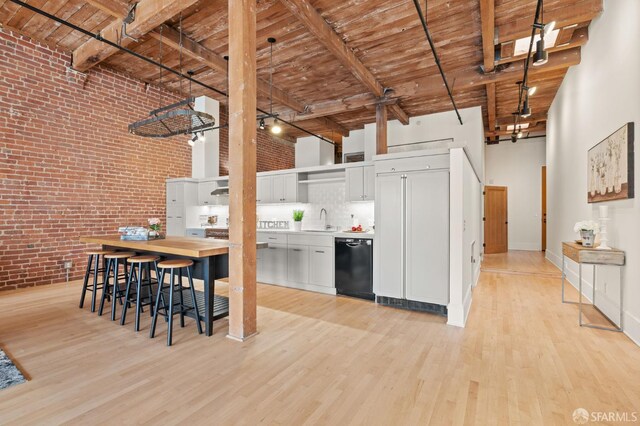 355 Bryant St Unit 411, San Francisco, CA 94107 - kitchen with brick wall, black dishwasher, a wooden ceiling with exposed beams, paneled built in fridge, and a high ceiling
