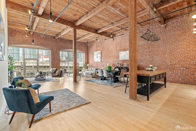 355 Bryant St Unit 411, San Francisco, CA 94107 - living room featuring brick wall, a wooden ceiling with exposed beams, wood finished floors, and a high ceiling