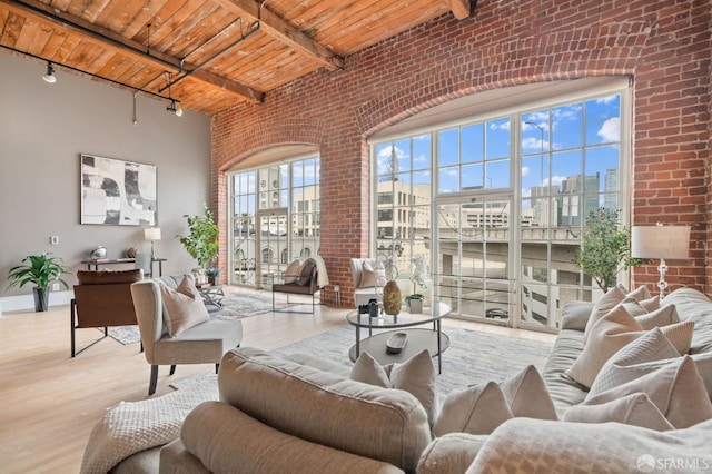 355 Bryant St Unit 411, San Francisco, CA 94107 - living room featuring a wood ceiling with exposed beams, brick wall, wood finished floors, track lighting, and a high ceiling