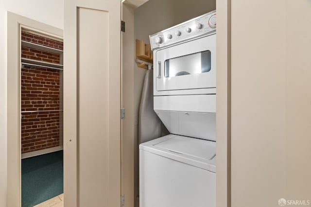 355 Bryant St Unit 411, San Francisco, CA 94107 - washroom with stacked washer and clothes dryer, brick wall, carpet flooring, and tile patterned flooring