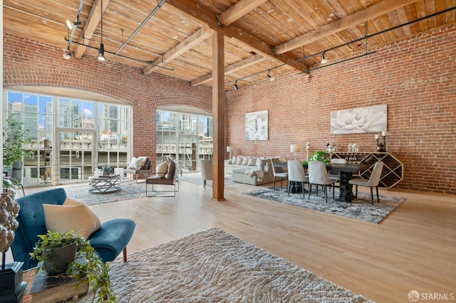 355 Bryant St Unit 411, San Francisco, CA 94107 - living room with brick wall, a wooden ceiling with exposed beams, wood finished floors, track lighting, and a high ceiling