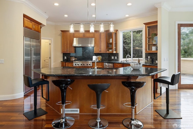 110 Sheridan Rd, Oakland, CA 94618 - kitchen featuring under cabinet range hood, stainless steel appliances, a sink, brown cabinets, and dark wood-style floors