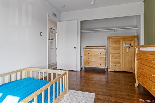 bedroom with dark hardwood / wood-style flooring and a closet