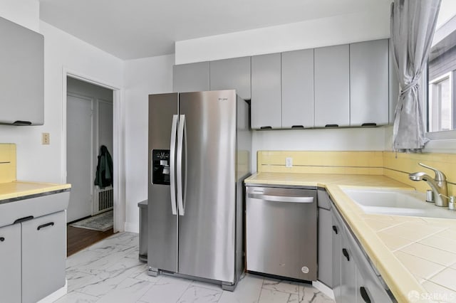 kitchen with sink, gray cabinets, backsplash, stainless steel appliances, and tile countertops