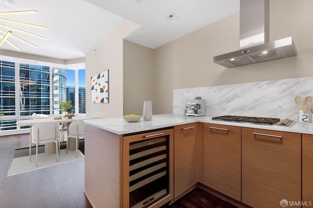 kitchen featuring beverage cooler, kitchen peninsula, dark hardwood / wood-style floors, and wall chimney range hood