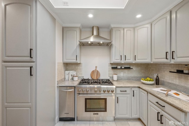 kitchen featuring wall chimney exhaust hood, white cabinetry, high end range, and crown molding