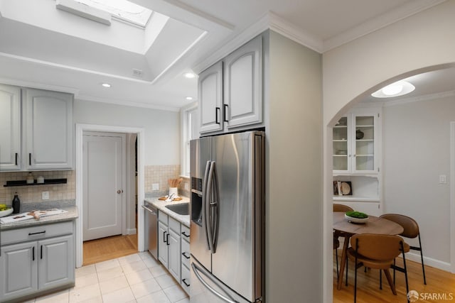 kitchen with stainless steel appliances, crown molding, and gray cabinets