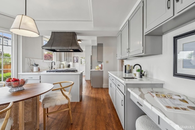 kitchen featuring wall chimney range hood, a wealth of natural light, and light countertops