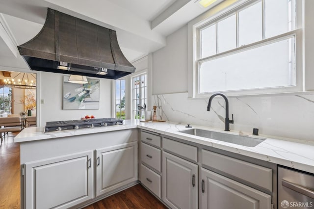 kitchen with a notable chandelier, a sink, stainless steel gas stovetop, island exhaust hood, and dark wood-type flooring